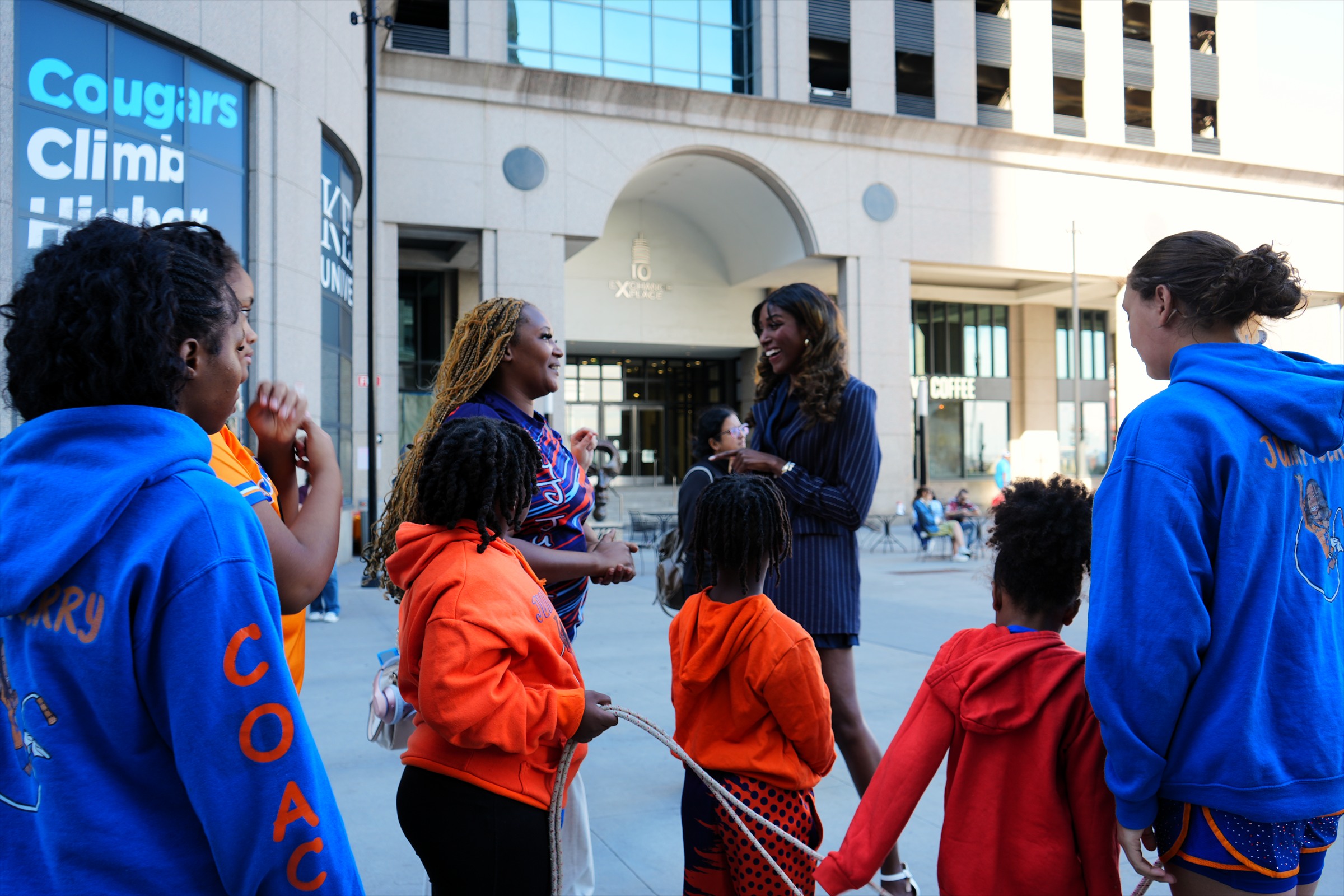 Adults and children in colorful event clothing speak together at Exchange Place during the march.