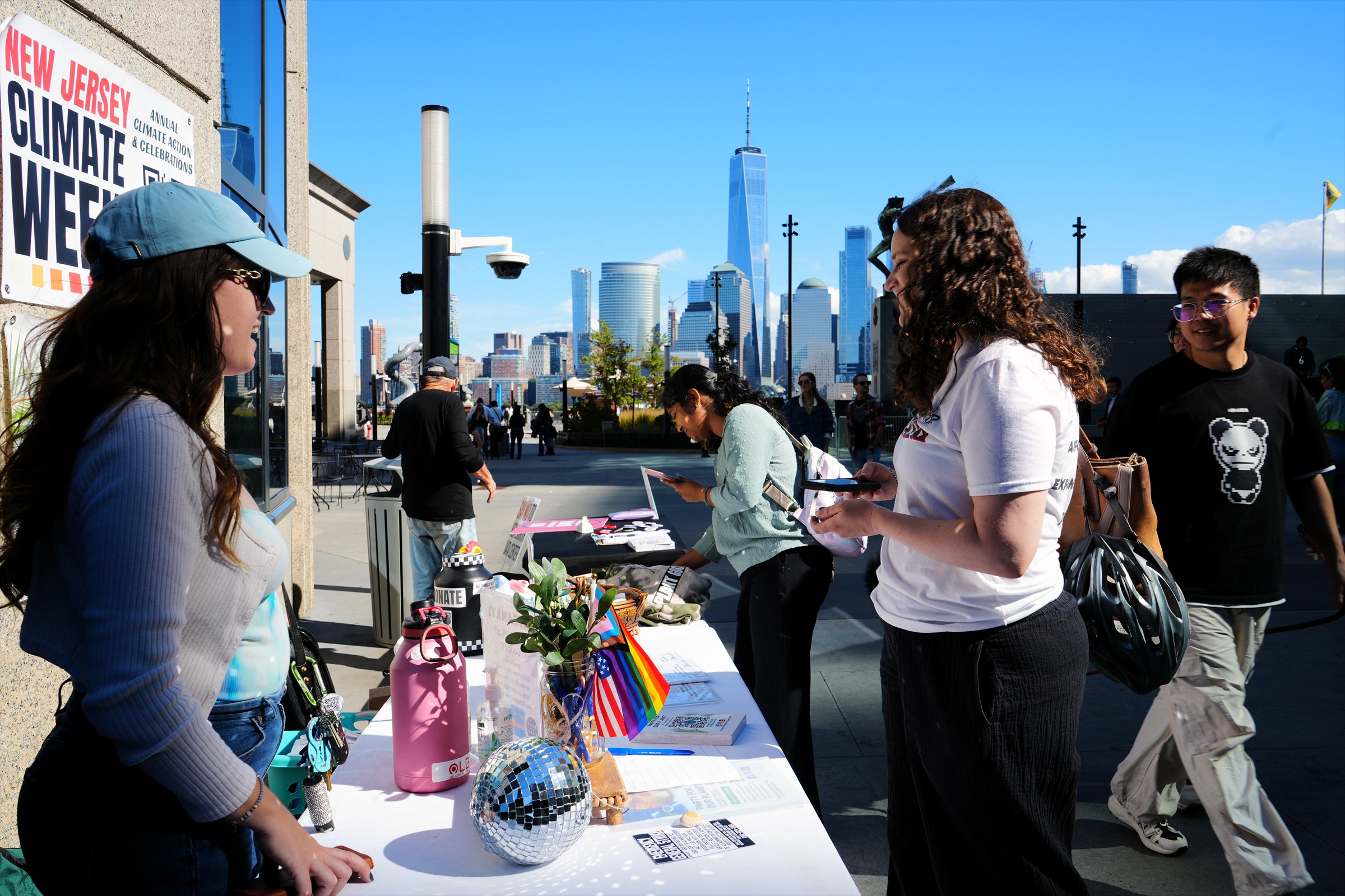 Participants gather at a waterfront information table with the Manhattan skyline across the river.